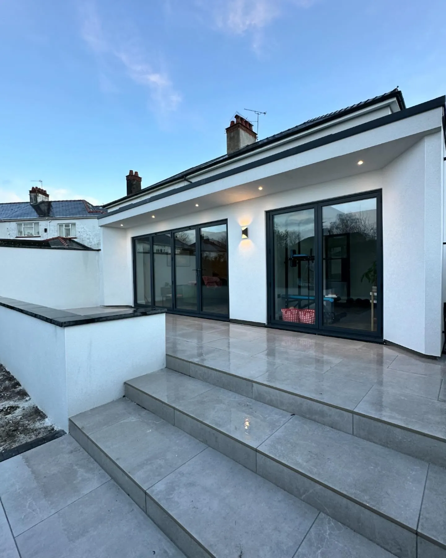 A white house with a large patio and steps leading to it.