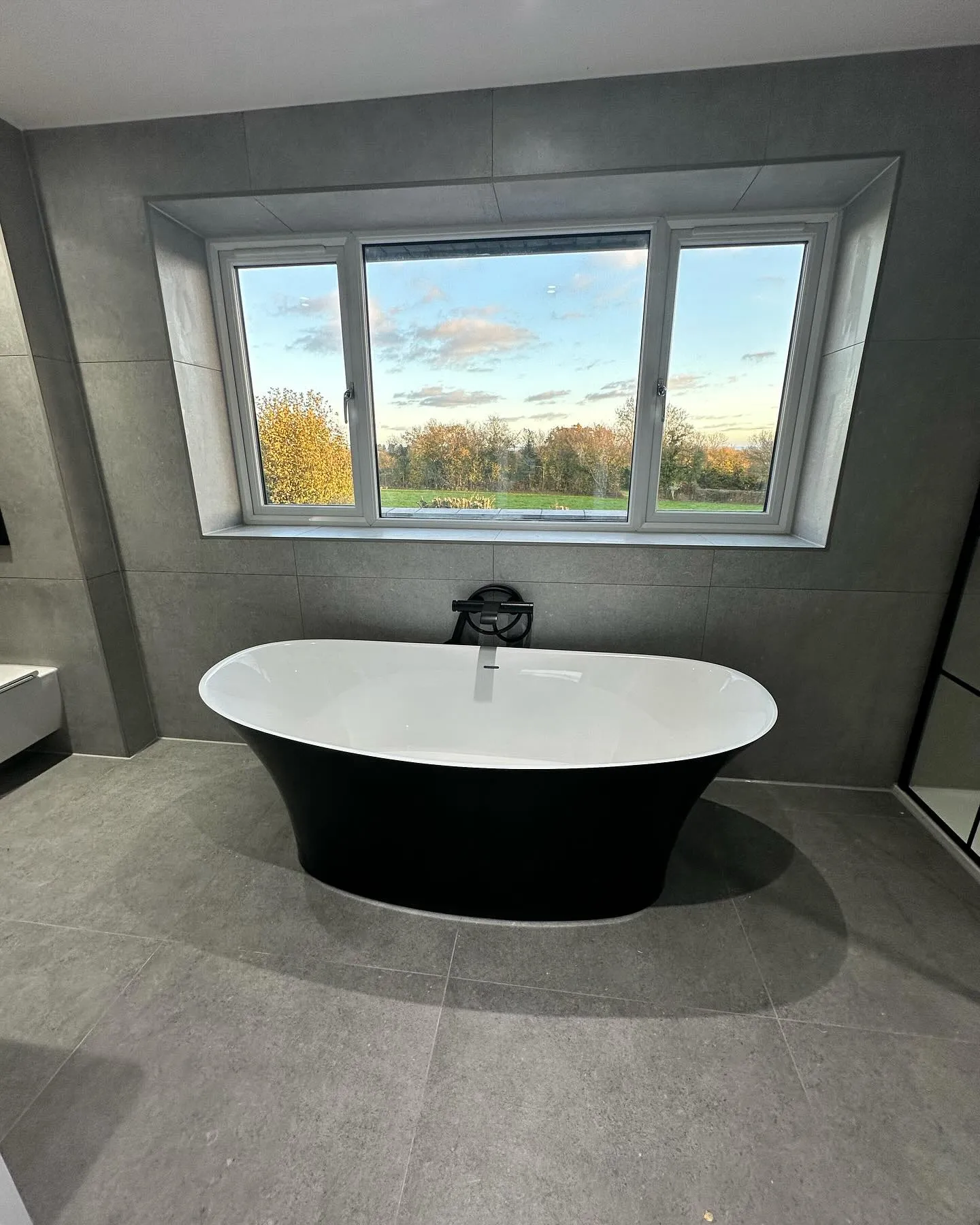 A bathtub in a bathroom with a large window.