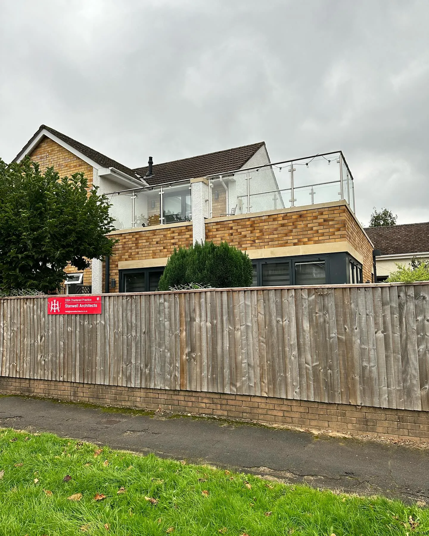 A house behind a fence with a sign on it.
