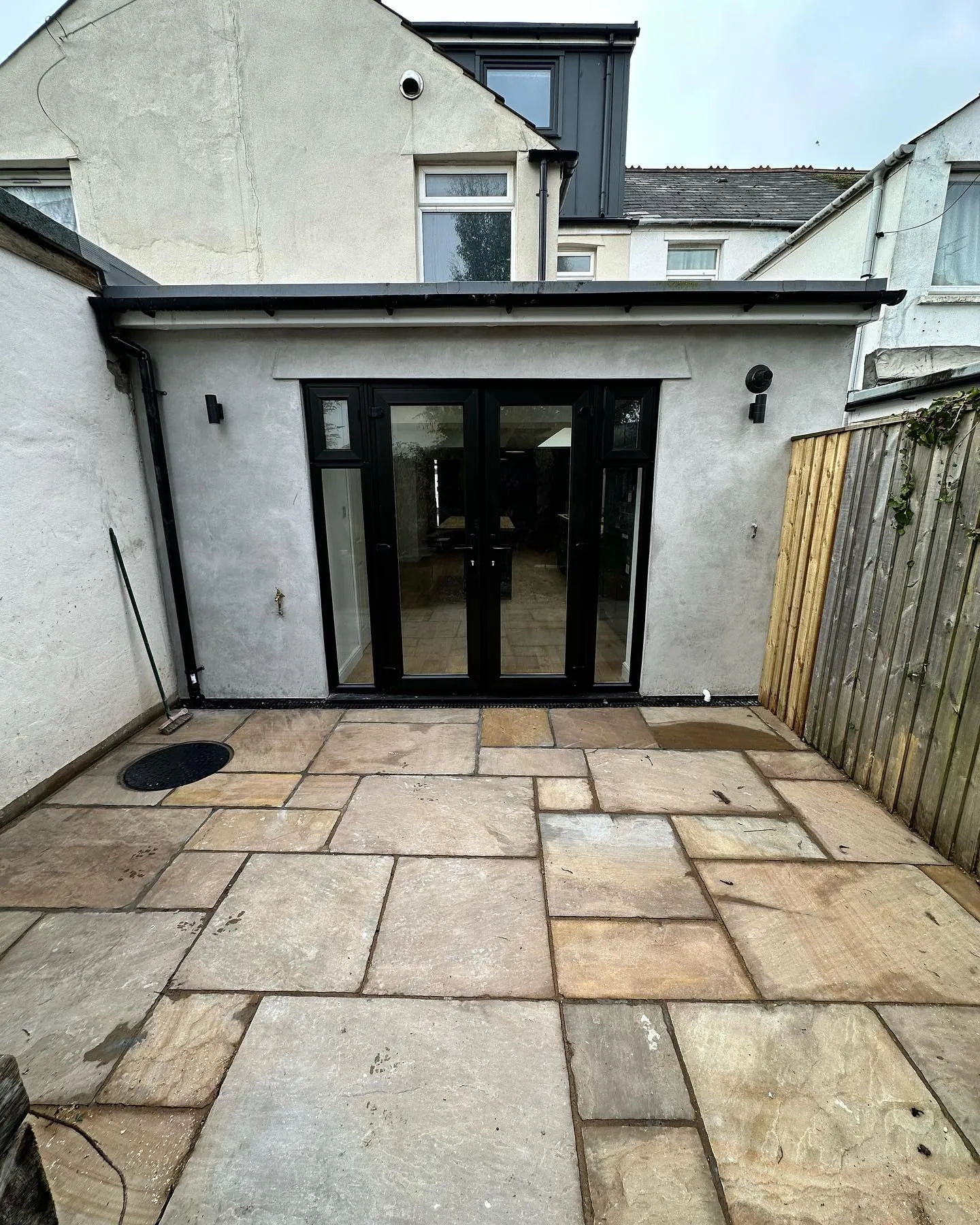 A back yard with a patio and sliding glass doors.